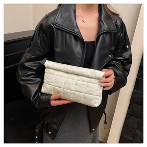 Detail view of a white quilted hand bag with glossy fabric texture and grid stitching