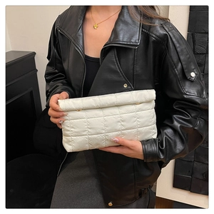 Close-up of quilted white nylon clutch featuring golden buttons and soft padded texture