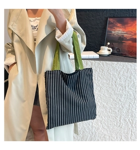 Detail of canvas tote bag with black and white stripes and vibrant green handles