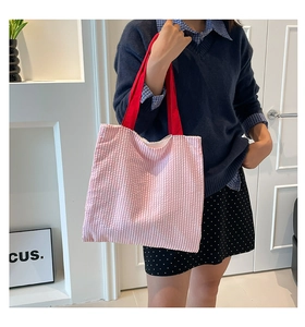 Détail du sac cabas en toile à rayures roses et blanches avec anses rouges