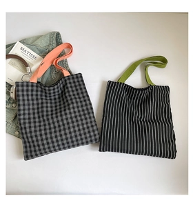 Flat lay of plaid and striped canvas tote bags with colorful handles and lifestyle props