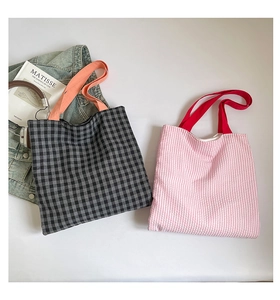 Flat lay of plaid canvas tote bags with colorful straps and artistic props on white background