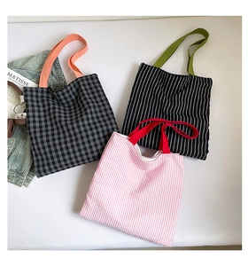 Detailed view of three checkered and striped canvas tote bags with colorful contrast handles