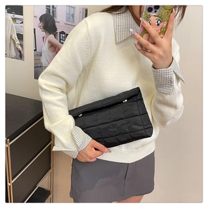 Close-up of black quilted handheld clutch bag with elegant square stitching texture