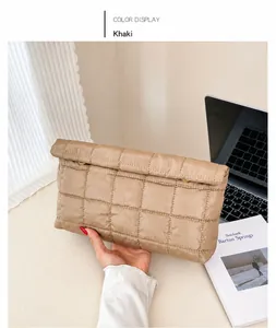 Détail d'une pochette matelassée kaki tenue par un mannequin dans un bureau chic