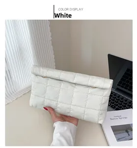 Détail d'une pochette matelassée blanche avec crochets métalliques et coutures carrées