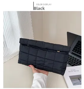 Détail d'une pochette matelassée noire avec fermoirs dorés et texture douce rembourrée