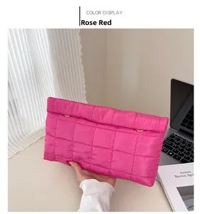 Détail d'une pochette matelassée rose fuchsia avec boucles dorées sur un bureau moderne