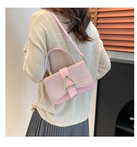 Detail of pink sequin handbag with gold D-ring buckle worn by model in chic outfit
