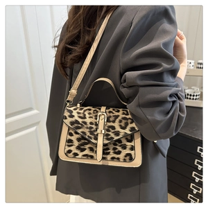 Close-up of leopard print crossbody bag with beige leather trim on model in a suit