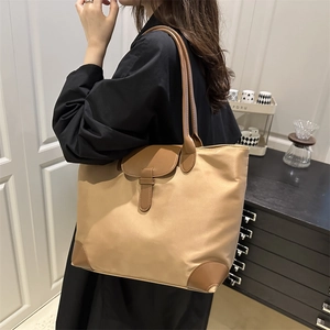 Large khaki nylon tote bag with brown leather trim and flap buckle for daily commute