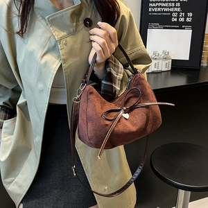 Brown suede bow handbag with heart pendant, versatile as a shoulder or crossbody bag