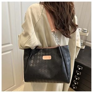 Model wearing a black quilted tote bag with pink leather and silver chain straps