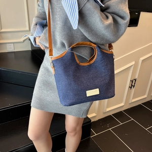 Sac seau chic en toile bleu denim avec bordures en cuir marron et bandoulière amovible