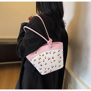 Close-up of women's cherry print bucket bag with pink knotted handles and silver rings