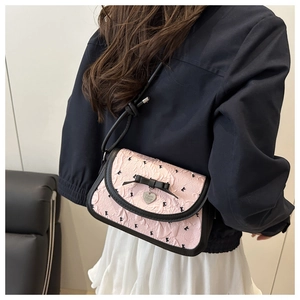 Détail du sac bandoulière en jacquard rose avec nœud noir et pendentif cœur argenté