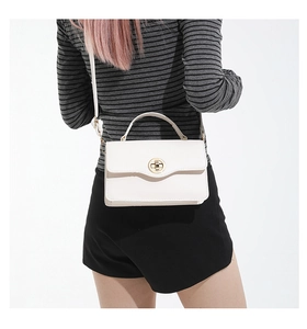Vue arrière d'un mannequin portant un petit sac carré blanc avec un fermoir doré chic