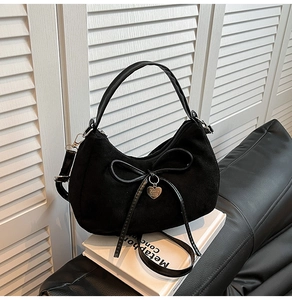 Detail of black crescent moon bag featuring suede texture and gold heart pendant