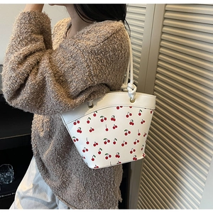 Detail of white bucket bag with cherry print and distinctive knotted rope handle texture