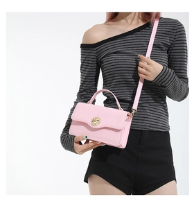 Détail du sac à main en cuir rose avec boucle dorée et bandoulière amovible