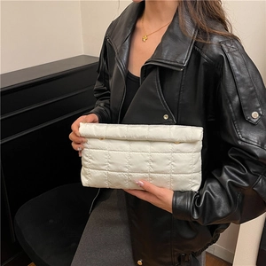 Quilted white clutch bag with padded texture and gold metal clasp held by a model
