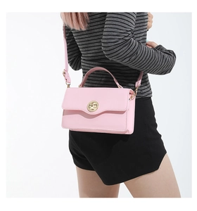 Détail du sac à bandoulière rose en similicuir avec fermoir rotatif doré circulaire