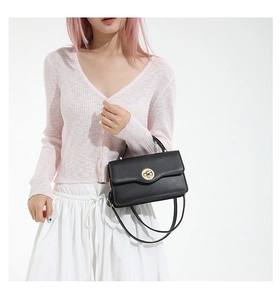 Détail d'un sac à bandoulière en cuir noir avec un fermoir rotatif doré sophistiqué