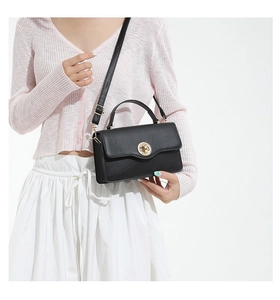 Détail du sac bandoulière en cuir noir avec fermoir doré rotatif et bandoulière réglable