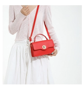 Détail d'un sac à main rouge en cuir avec boucle dorée porté par un mannequin