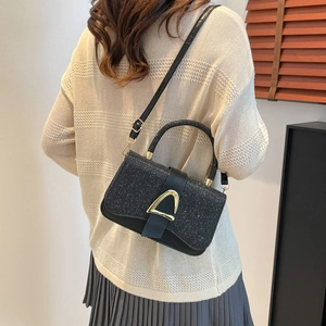 Minimalist black sequin crossbody bag with golden triangle buckle on model