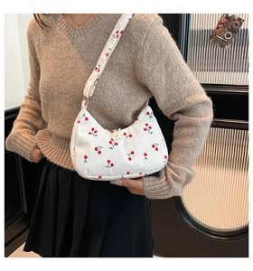 Model showing white corduroy shoulder bag with cherry pattern and a round minimalist shape