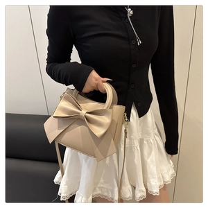 Close-up of the elegant bow detail and soft matte leather texture on this beige handbag