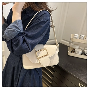 Sac sous le bras chic en cuir beige avec boucle dorée, porté par un mannequin en décor moderne