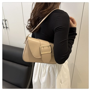 Beige leather underarm bag with gold buckle shown on shoulder for commute style