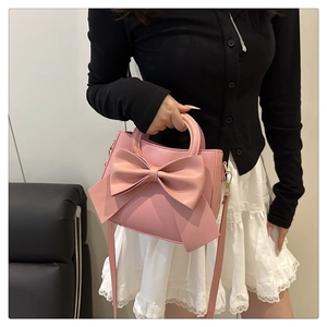 Close-up of a pink mini square handbag with a large bow detail and elegant top handle