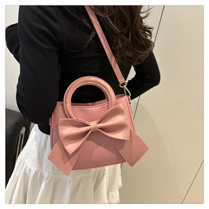 Detail view of the pink bucket bag featuring a large bow and gold metal hardware hooks