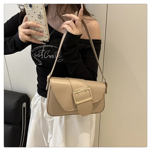 Detail showing the large gold metal buckle on a beige minimalist faux leather bag