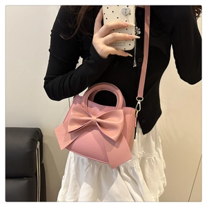Detailed shot of pink leather handbag with a large bow detail and light gold hardware