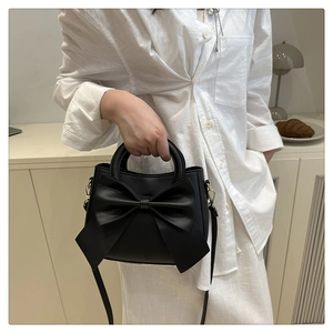 Close-up of elegant black handbag with large bow detail and matte leather texture