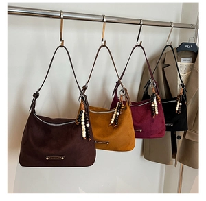 Detailed view of four suede dumpling bags in autumn colors with wooden bead charms