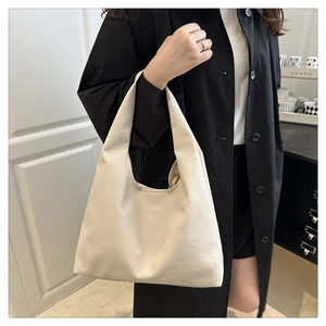 Détail d'un sac cabas minimaliste en cuir beige porté par un mannequin pour le travail