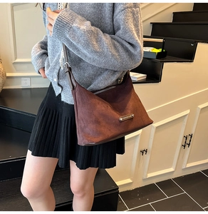 Detailed view of brown matte suede hobo bag with adjustable strap and metal logo plate