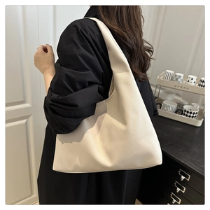 Sac hobo minimaliste beige avec texture cuir grainé porté par un mannequin au quotidien