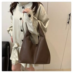 Détail du grand sac cabas en cuir marron foncé avec texture grainée porté par un mannequin