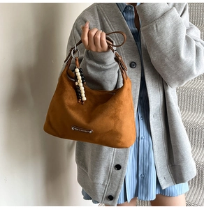 Brown suede hobo bag with leather strap and wooden bead charm shown on model