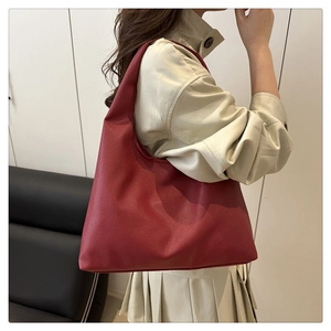 Close-up of a large burgundy tote bag with lychee leather texture worn by a model