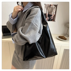 Detail of the black glossy leather shoulder bag in a minimalist crescent pleated design