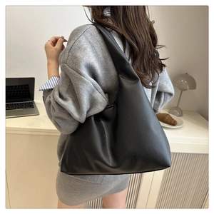Close-up of a large black hobo bag with pebble texture showing capacity in a home office setting