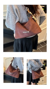 Detail of dark brown suede crescent tote with colorful bead charms and silver logo plate