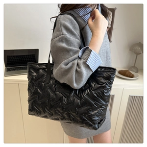 Détail du sac cabas matelassé noir en duvet avec texture tissée et finition brillante